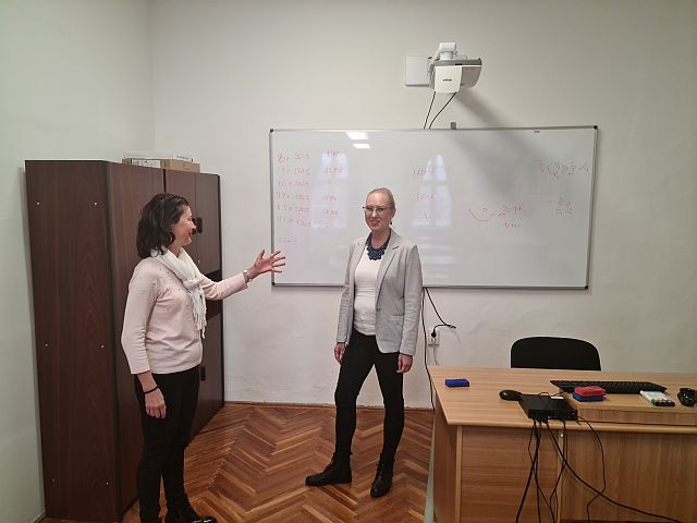 Irodában előadásra készül 2 hölgy egy whiteboard és ez szekrény előtt beszélgetnek